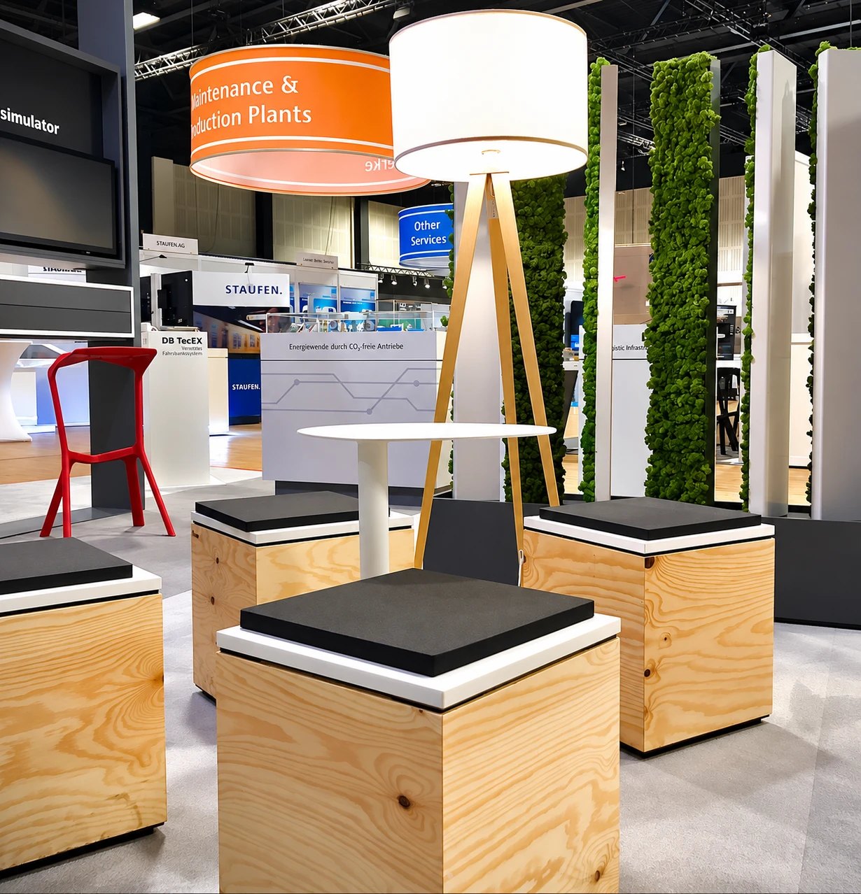 Lounge auf einem Messestand mit Sitzwürfeln aus Holz, Stehtisch und Stehleuchte